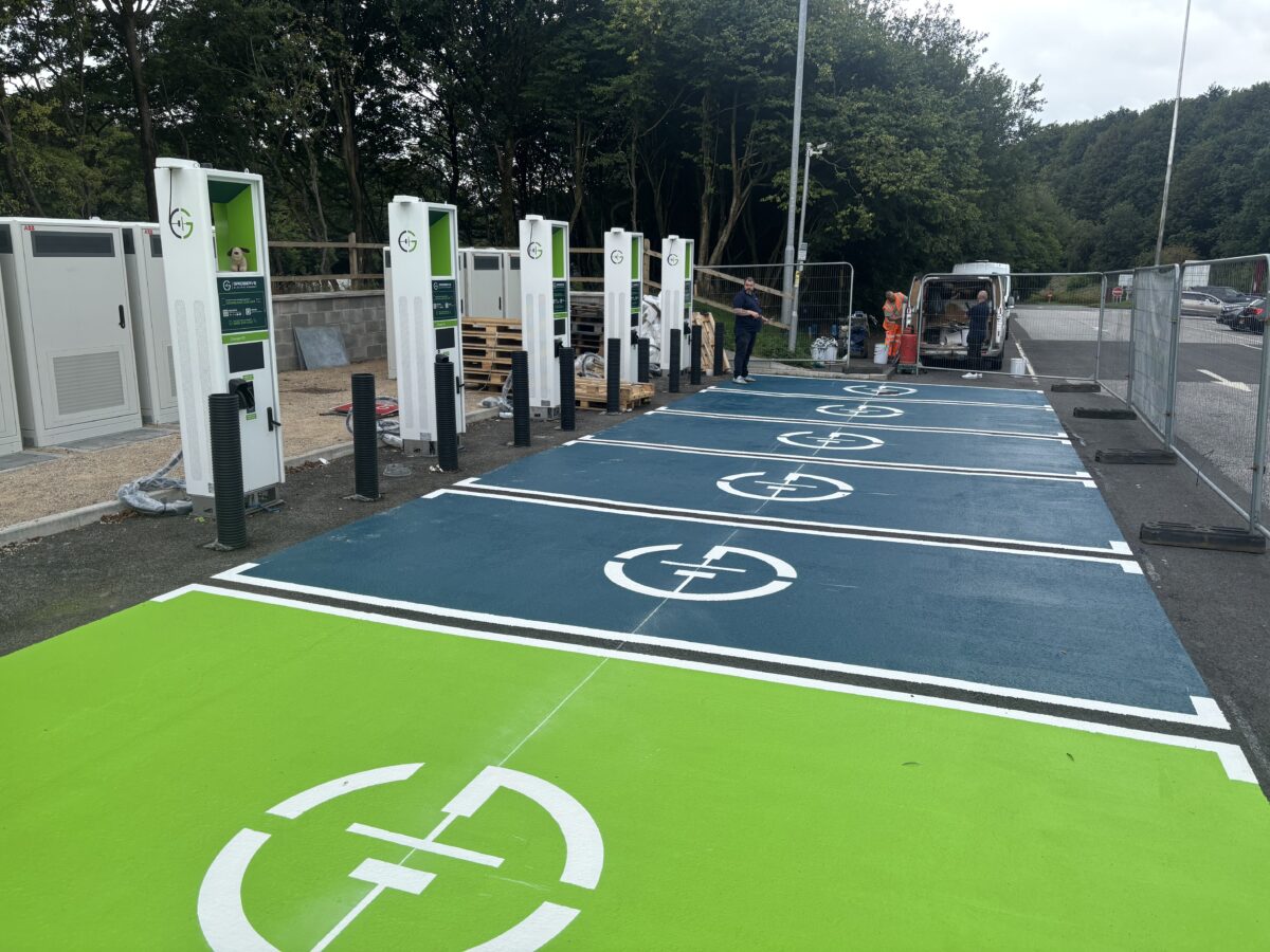 Smart charging stations, with floor graphics in vivid blue and green and the company logo in white over the top. 